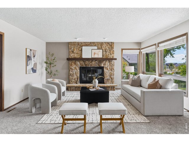 Property Photo 4 Light-filled living room anchored by a beautiful stone fireplace.