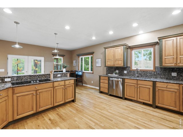 Property Photo 13 Granite counters, hardwood floors, and generous cabinetry in the kitchen.