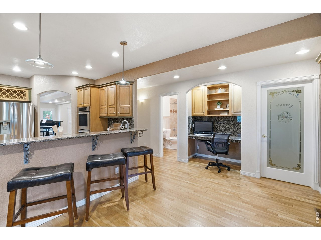 Property Photo 15 Bar seating, a built-in desk nook, and an etched-glass door to the walk-in pantry.