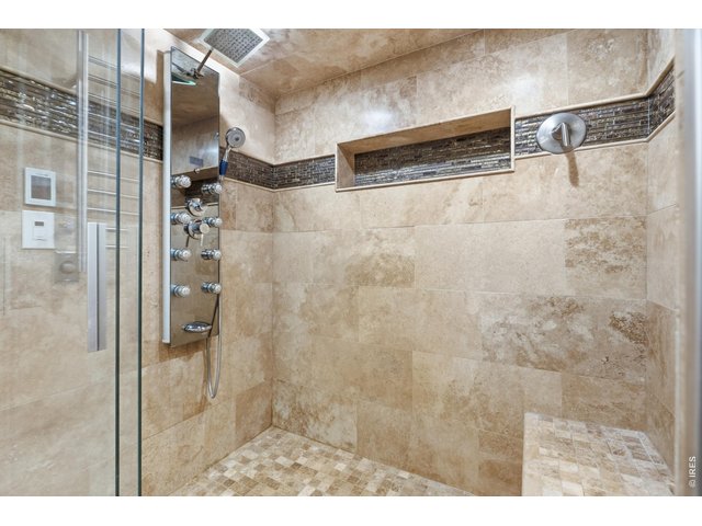 Property Photo 21 Travertine surround, rain head, and a multi-jet shower panel in the primary bath.