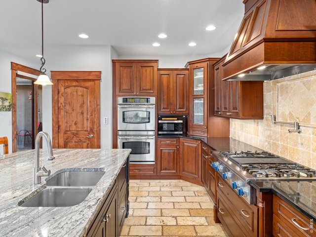 Property Photo 17 The gourmet kitchen is a chef's dream, featuring granite countertops, premium stainless steel appliances, a Thermador range with pot filler, double ovens, large island and abundant space for gathering with family and friends.