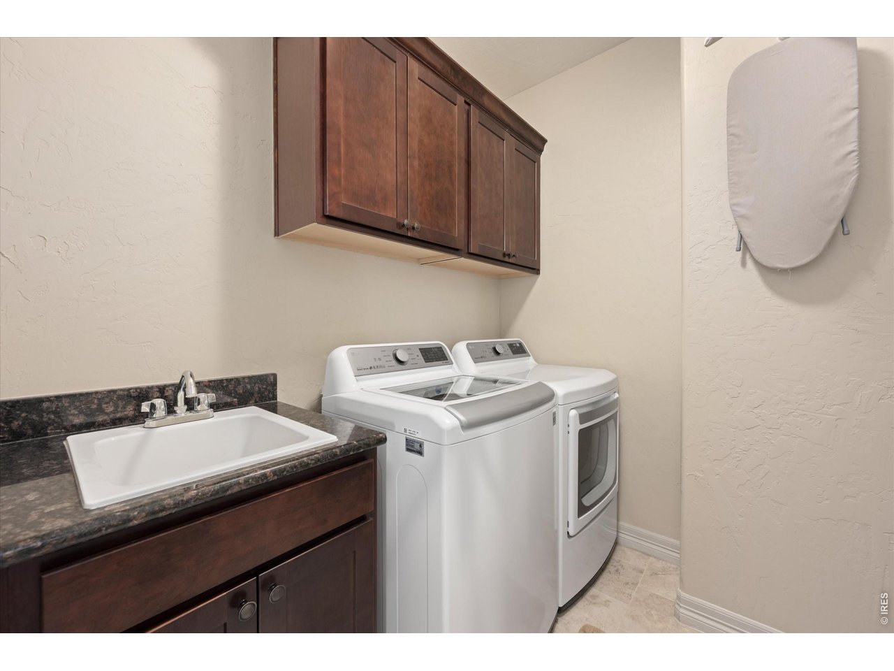 Property Photo 19 Main Floor Laundry Room with Sink, Upper Cabinetry & Tiled Flooring
