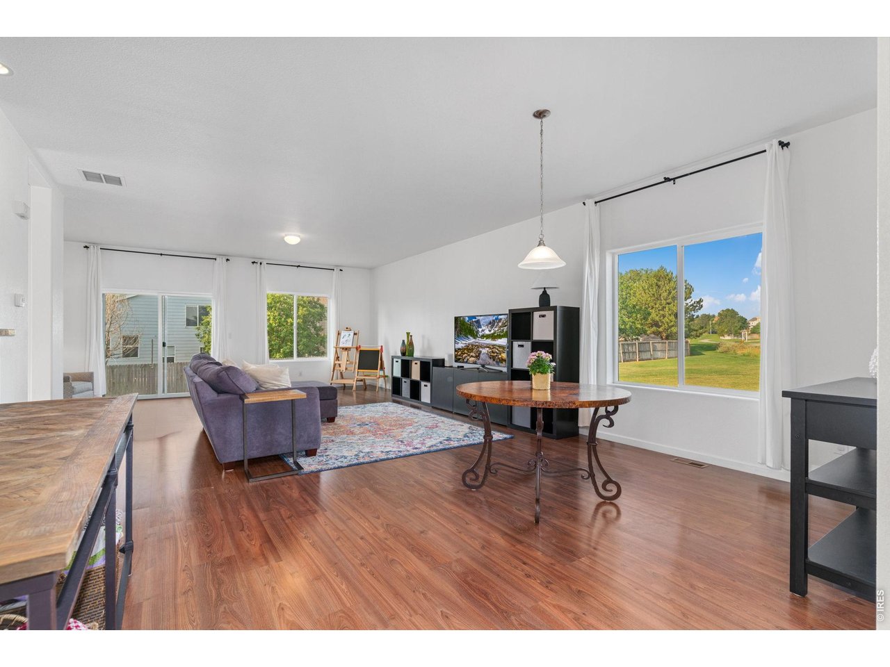 Property Photo 5 The dining room flows directly into the living room! Natural light fills the space with all of the large windows and the sliding glass door out to the back yard.