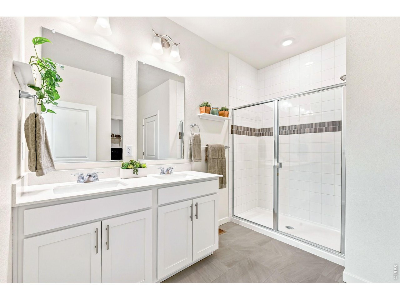 Property Photo 15 Primary bathroom with dual sinks, quartz vanity, and tiled shower.