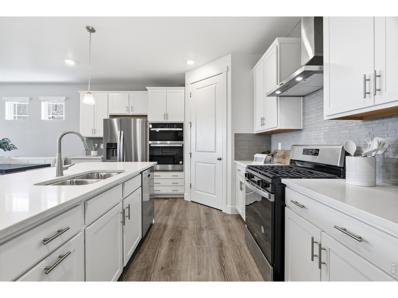 Property Photo 8 Double ovens, a gas range, and a tile backsplash outfit the main-level kitchen.