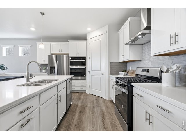 Property Photo 8 Double ovens, a gas range, and a tile backsplash outfit the main-level kitchen.