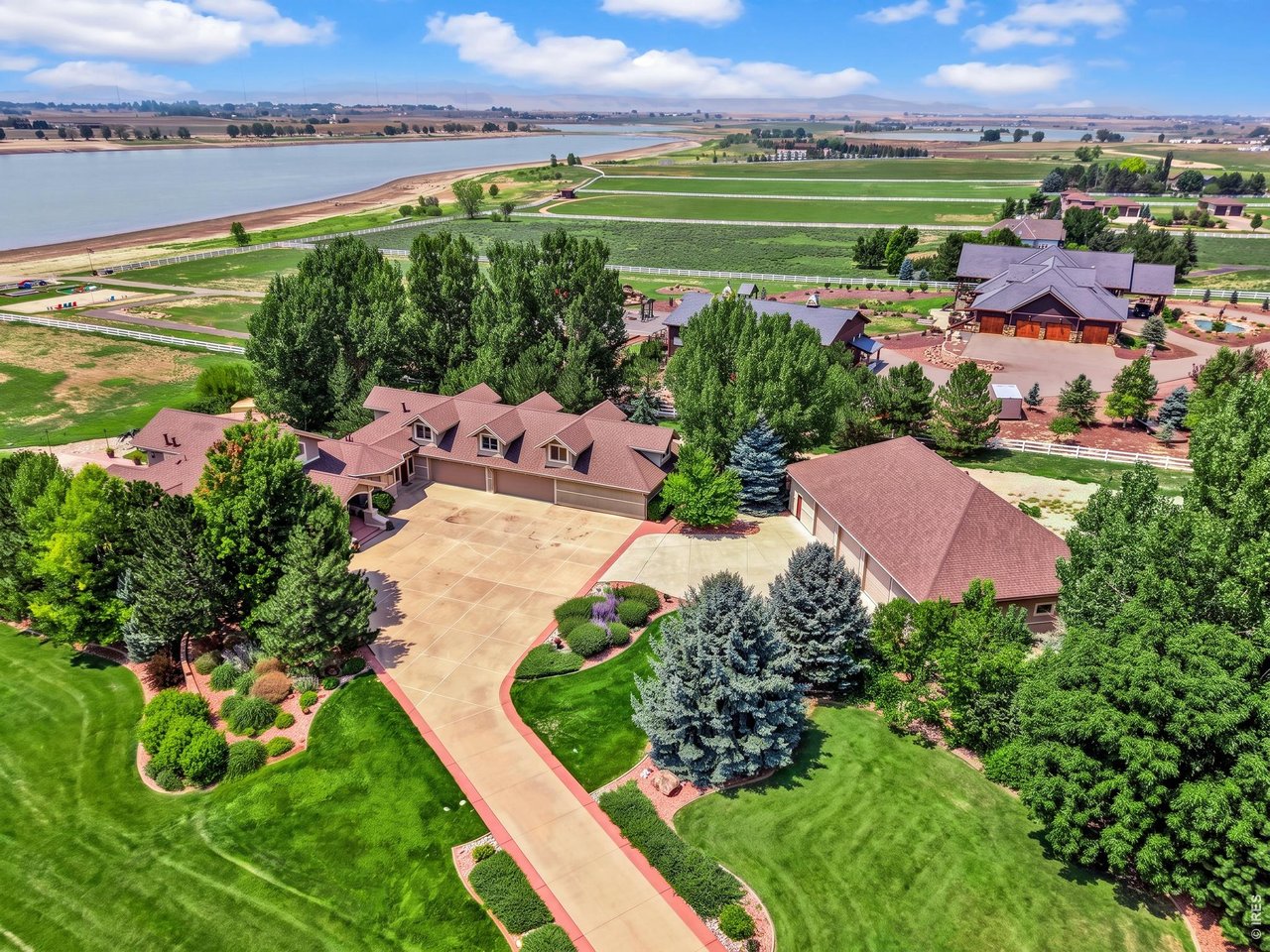 Property Photo 6 Expansive estate setting with beautifully landscaped grounds and sweeping reservoir and Front Range views. Aerial view of the property and surrounding reservoir. Grass color has been enhanced in professional photography.
