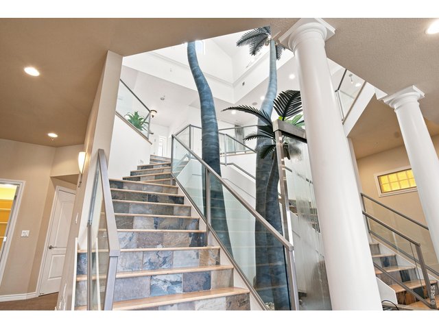 Property Photo 25 Dramatic custom staircase with glass railings surrounds a striking water feature.