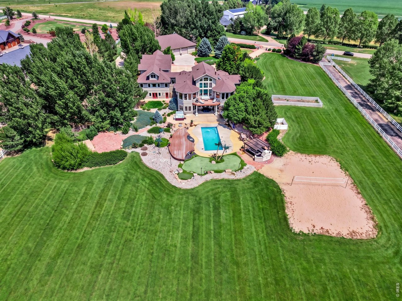 Property Photo 1 Aerial view showcasing the home's impressive outdoor amenities, including pool, hot tub, putting green and expansive landscaped grounds. Aerial view of the property and surrounding reservoir. Grass color has been enhanced in professional photography.