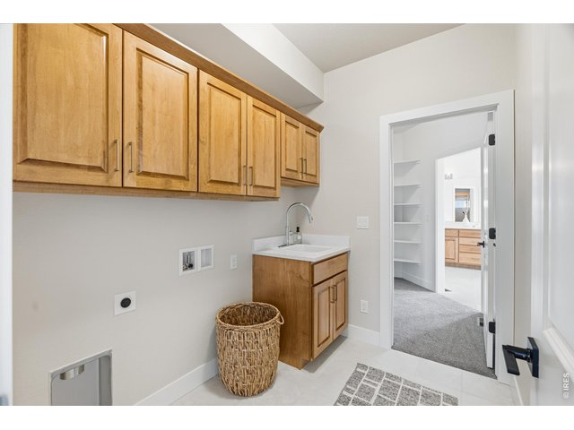 Property Photo 28 Well-appointed laundry room with upper cabinetry, utility sink, and functional layout connecting to primary closet.