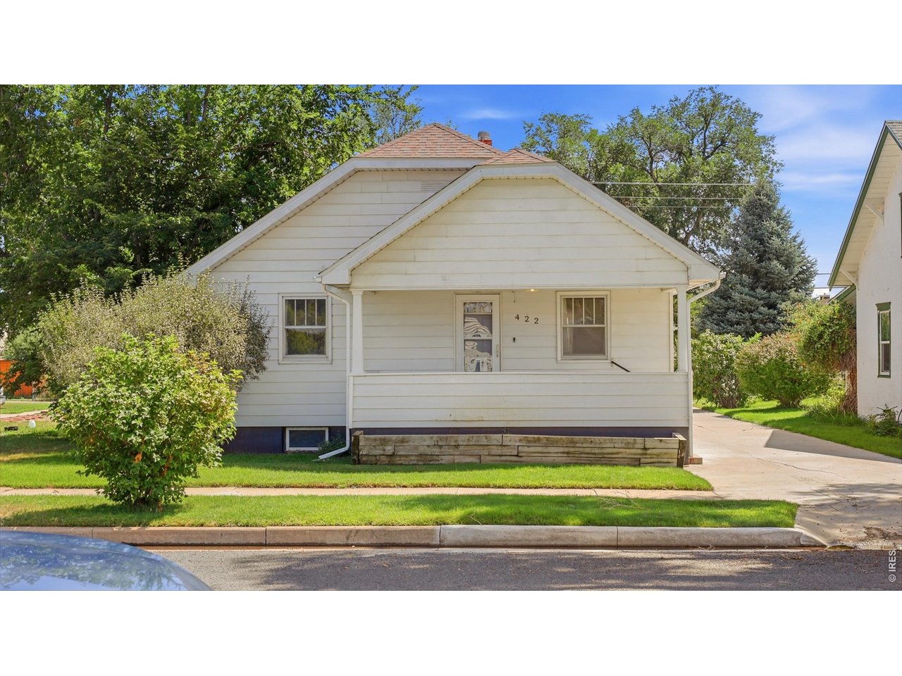 Property Photo 3 Front exterior with mature landscaping and covered porch.