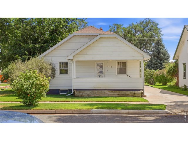 Property Photo 3 Front exterior with mature landscaping and covered porch.