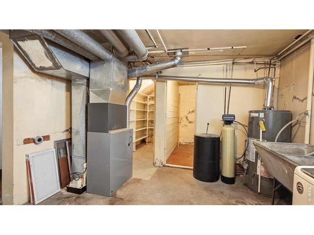 Property Photo 21 Additional view of the basement utility area with furnace, water heater, and storage space.