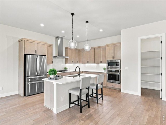 Property Photo 7 Large windows flood the home with natural light throughout the day. Stylish pendant lighting highlights the expansive island. The Zephyr chimney hood adds a sleek designer touch.