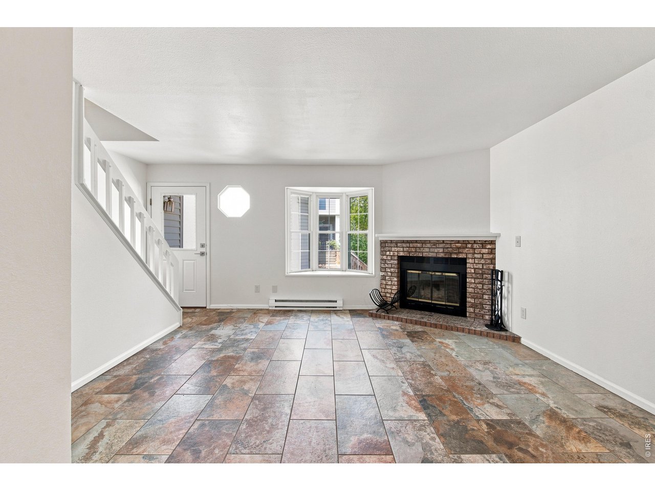 Property Photo 8 Bright and inviting living room featuring a wood-burning fireplace, abundant natural light, and a fresh, move-in-ready feel.