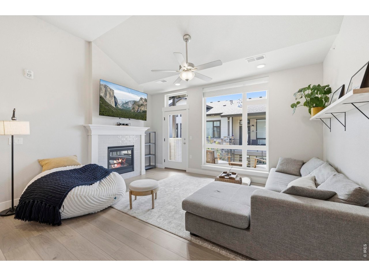 Property Photo 13 living room has vaulted ceiling, transom windows for extra light, ceiling fan, and fireplace