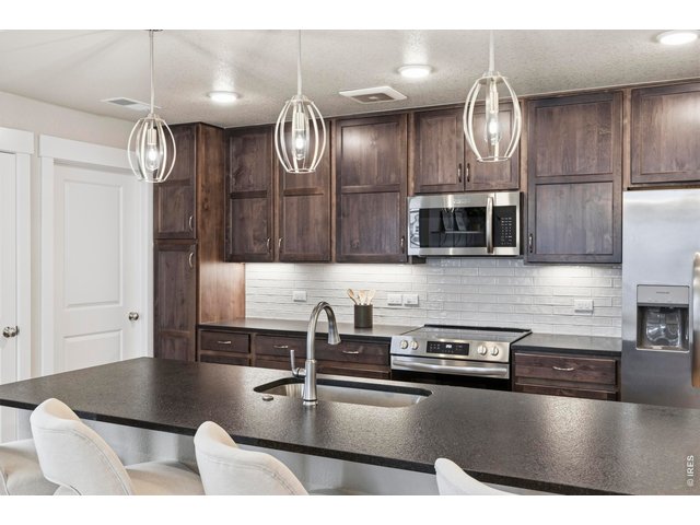 Property Photo 9 Huge breakfast bar provides an expansive workspace, complemented by stylish drop-down lighting that enhances the overall ambiance.