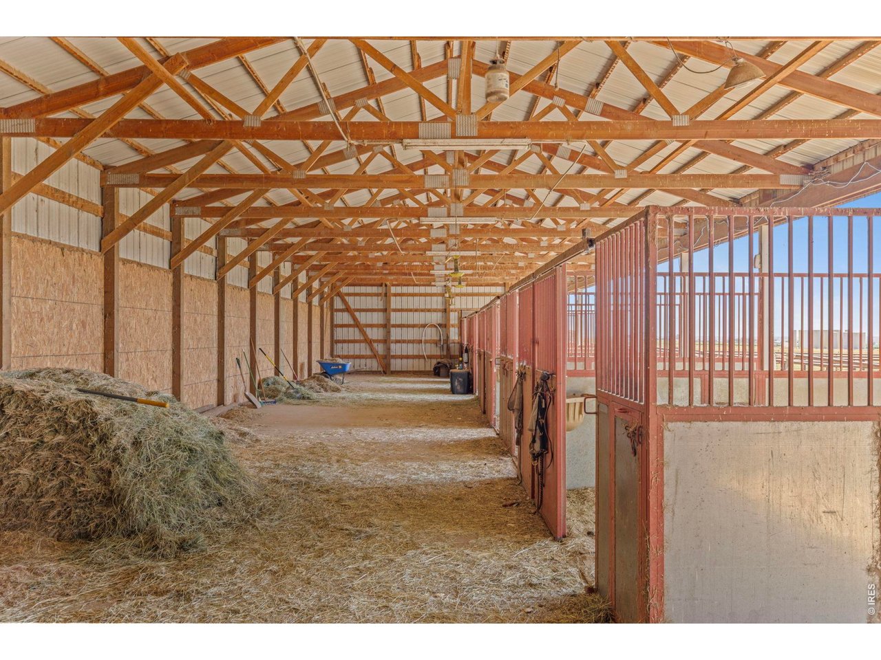 Property Photo 26 Functional barn interior with covered aisle, stalls and space for hay and equipment.