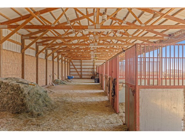 Property Photo 26 Functional barn interior with covered aisle, stalls and space for hay and equipment.