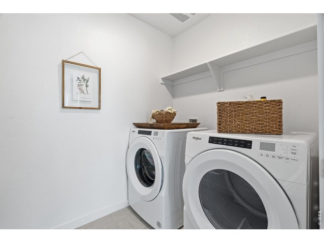 Property Photo 25 Dedicated upstairs laundry with full-size Whirlpool washer and dryer plus overhead shelving, included with the home.