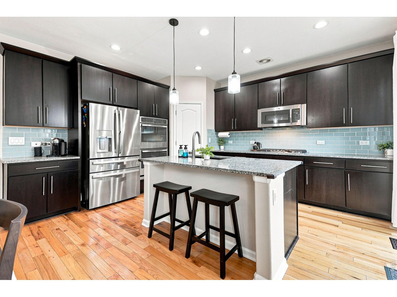 Property Photo 4 The gourmet kitchen is designed for both cooking and entertaining, featuring a gas cooktop, double ovens, upgraded refrigerator, large island, abundant cabinetry, pantry, and a comfortable eat-in area