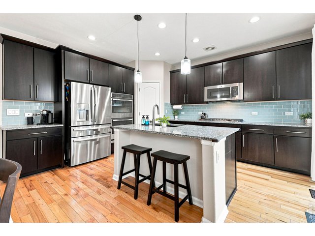 Property Photo 4 The gourmet kitchen is designed for both cooking and entertaining, featuring a gas cooktop, double ovens, upgraded refrigerator, large island, abundant cabinetry, pantry, and a comfortable eat-in area