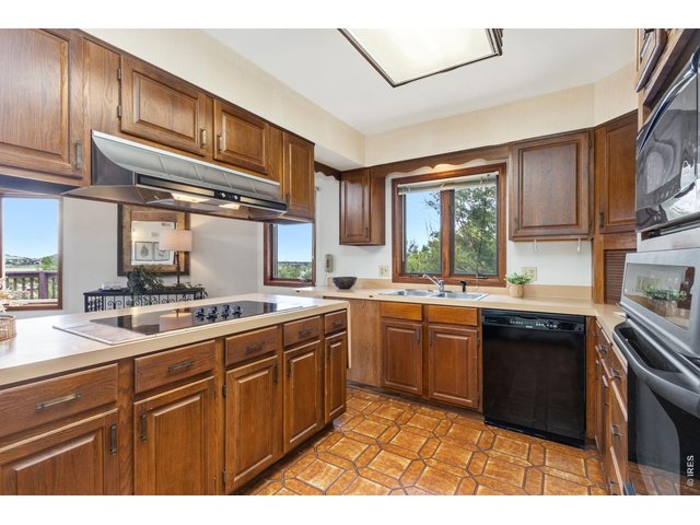 Property Photo 21 Spacious kitchen featuring convenient pull-out cabinet storage, a built-in cooktop, and a vent hood.