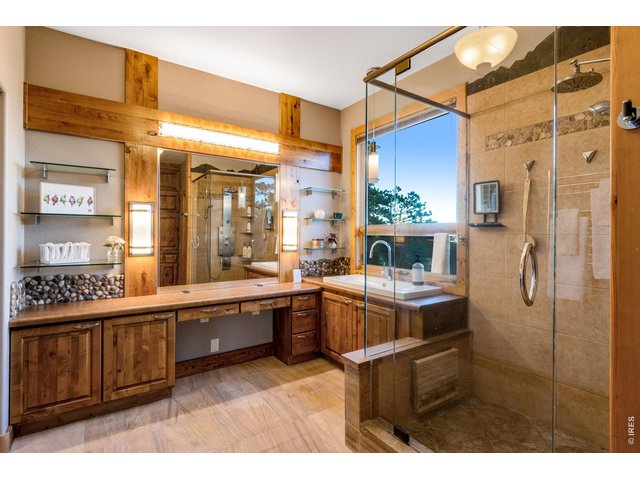 Property Photo 29 walk-in closet, luxury private bath featuring built-in cabinetry, sandstone tile flooring with radiant in-floor heat, heated towel rack, shower with overhead + 6 body jets and a wand, 2 lifted vanities, door to throne, glass shelving