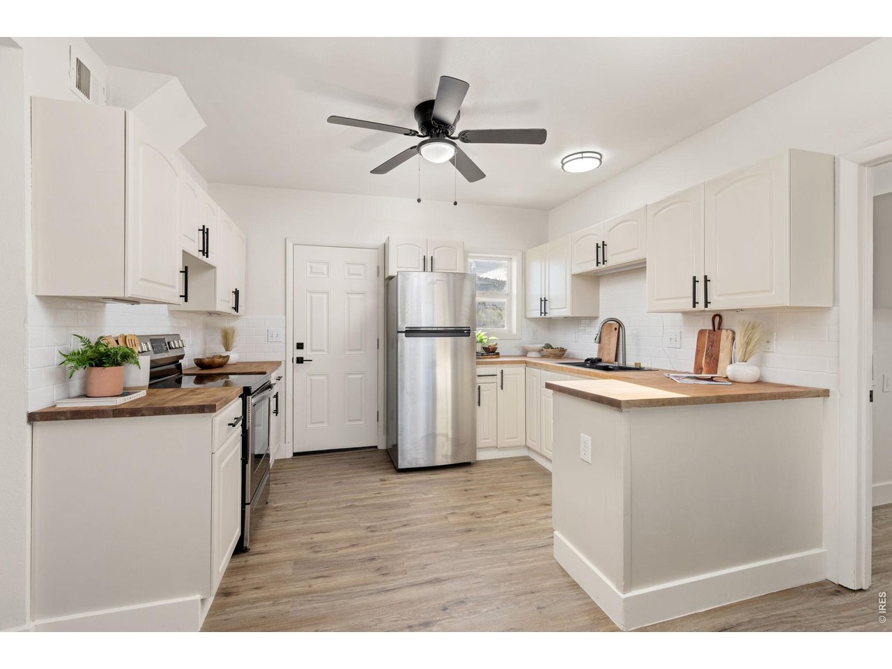 Property Photo 10 Updated kitchen features a functional layout with generous cabinetry, butcher-block countertops and stainless steel appliances.