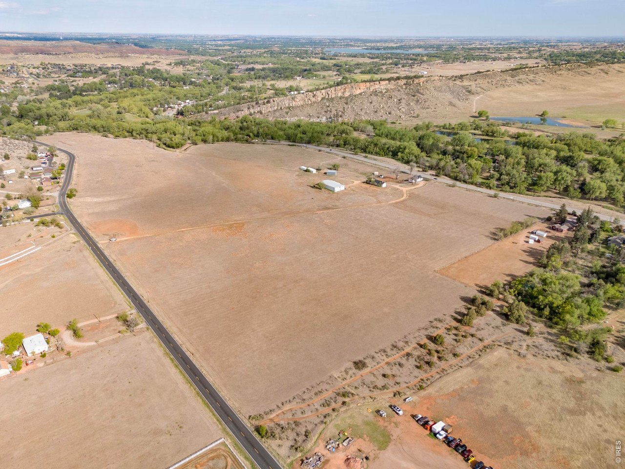 Property Photo 2 Expansive aerial view showcasing the property's open acreage, mature tree corridors and convenient West Loveland location.