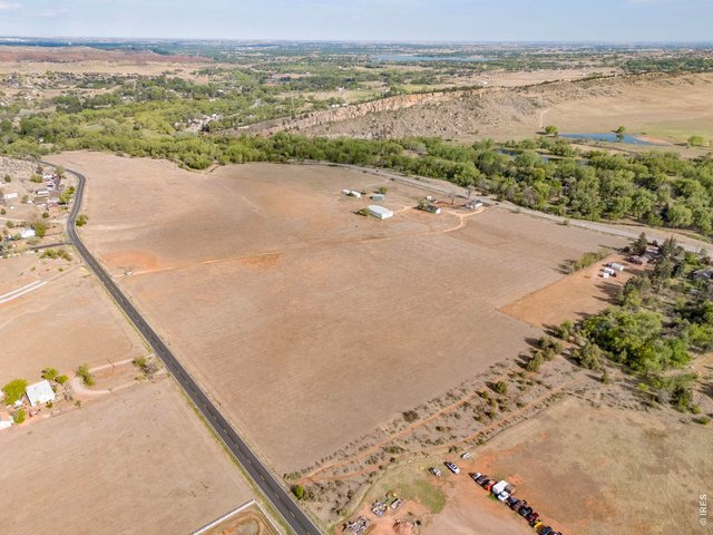 Property Photo 2 Expansive aerial view showcasing the property's open acreage, mature tree corridors and convenient West Loveland location.