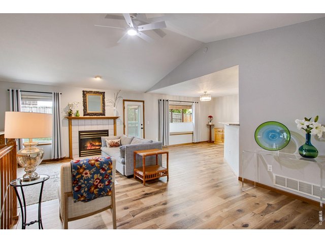 Property Photo 8 Large central living room featuring vaulted ceilings, new ceiling fan and a center gas fireplace with blower, mantel, and tile backsplash