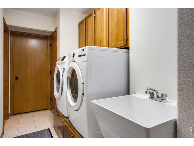 Property Photo 27 Main floor laundry is located off garage for convenience and features a pocket door, cabinets, utility sink, tile flooring, coat/broom closet plus washer and dryer on risers which are included