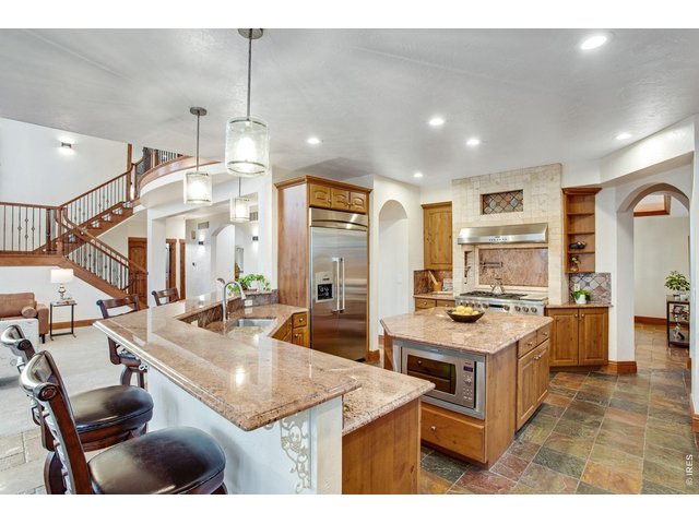 Property Photo 23 Gourmet kitchen features center island, wrap around breakfast bar, pantry, knotty alder cabinets with hardware and roll-out drawers, granite slab countertops, 2 sinks, full copper quartzite flooring and backsplash with bronze metal accents