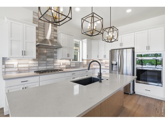 Property Photo 4 Designer kitchen featuring quartz countertops, custom cabinetry, statement lighting, and an oversized island perfect for gathering.