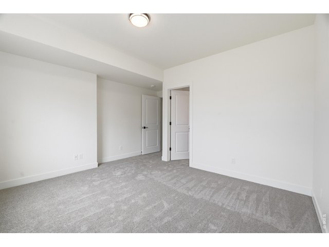 Property Photo 21 Spacious lower-level bedroom with plush carpeting and convenient access to nearby storage and bath.
