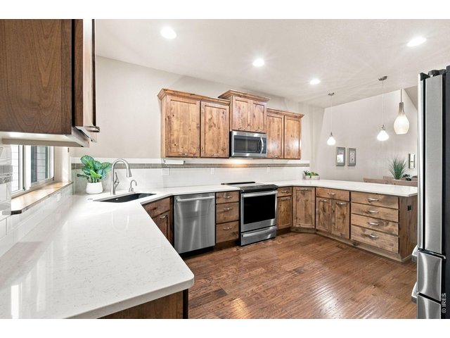 Property Photo 3 Spacious kitchen featuring beautiful wood cabinetry, expansive solid-surface countertops, stainless steel appliances, tile backsplash and abundant prep and storage space.