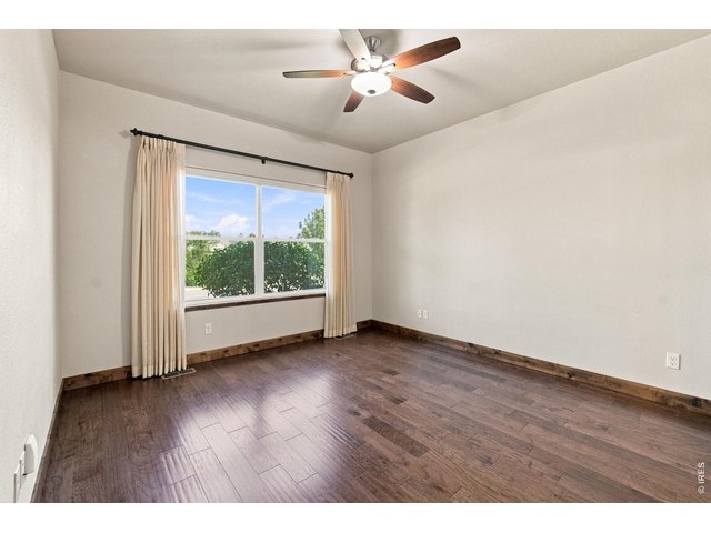 Property Photo 10 Spacious Primary main-level bedroom with hardwood flooring, ceiling fan and a large window providing wonderful natural light.