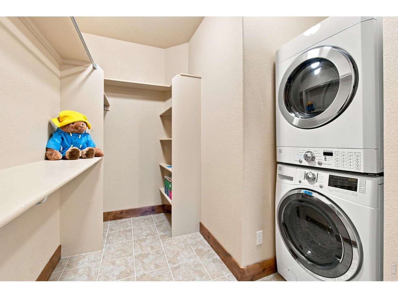 Property Photo 16 Convenient laundry area with stacked washer and dryer, built-in shelving, hanging space and additional storage.