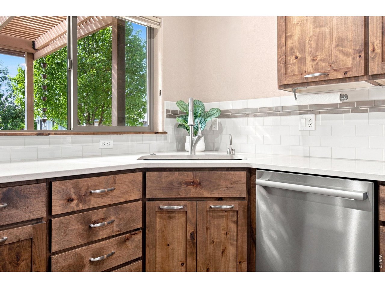 Property Photo 6 Beautiful wood cabinetry, bright countertops, stainless steel appliances and a stylish tile backsplash create a warm, inviting kitchen.