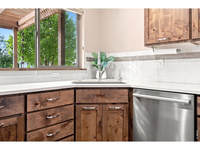 Property Photo 6 Beautiful wood cabinetry, bright countertops, stainless steel appliances and a stylish tile backsplash create a warm, inviting kitchen.