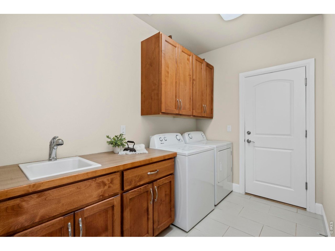 Property Photo 28 The laundry room is located on the main floor near the garage entry and features matching cabinetry, a utility sink, and additional storage space.