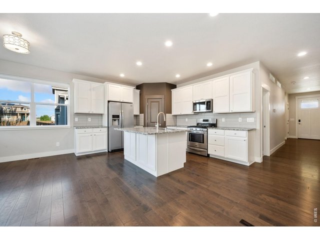 Property Photo 9 Kitchen with stainless steel appliances and white cabinets.