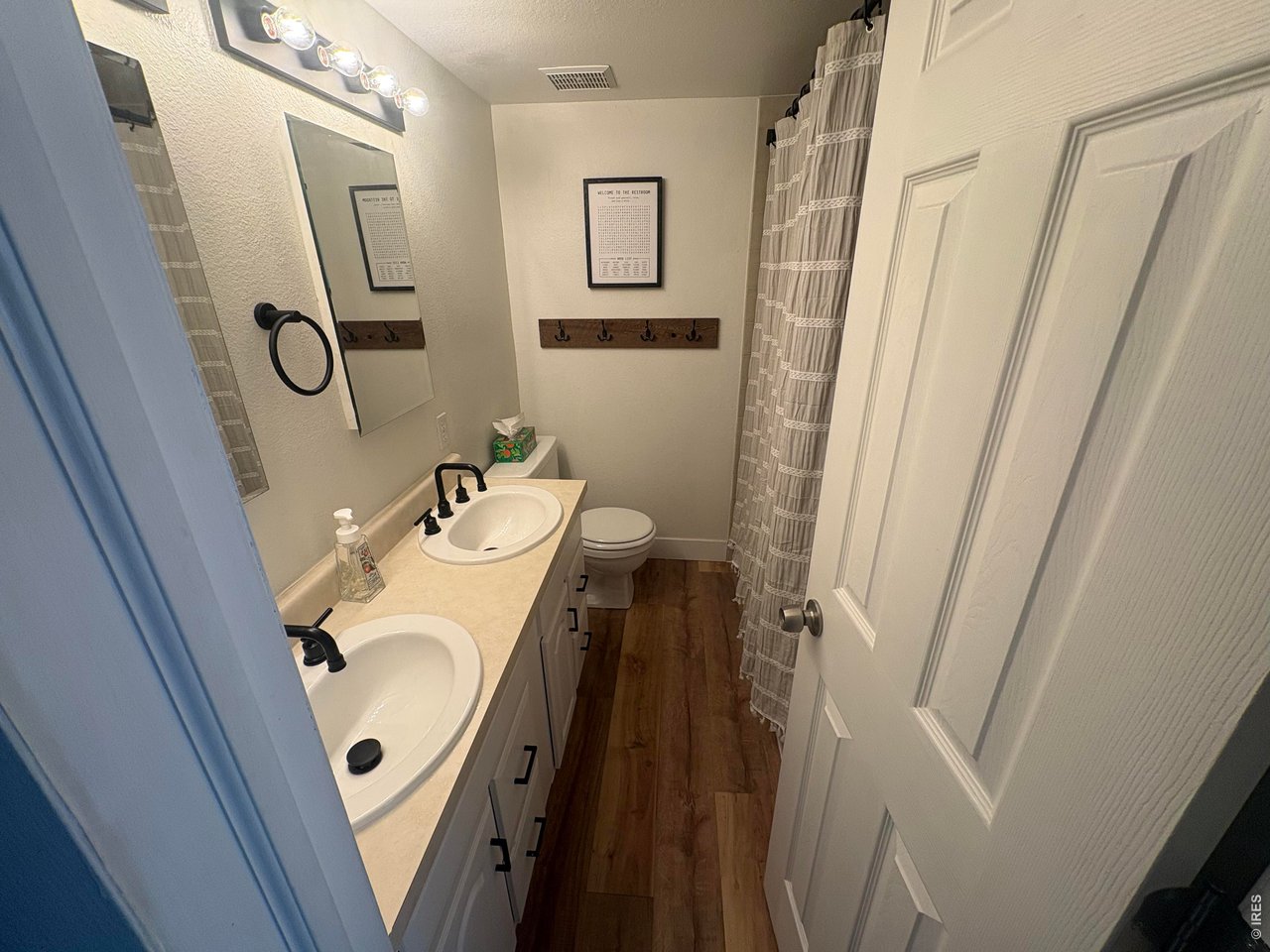 Property Photo 21 Shared full primary bathroom with dual sinks and LVP flooring on upper level.