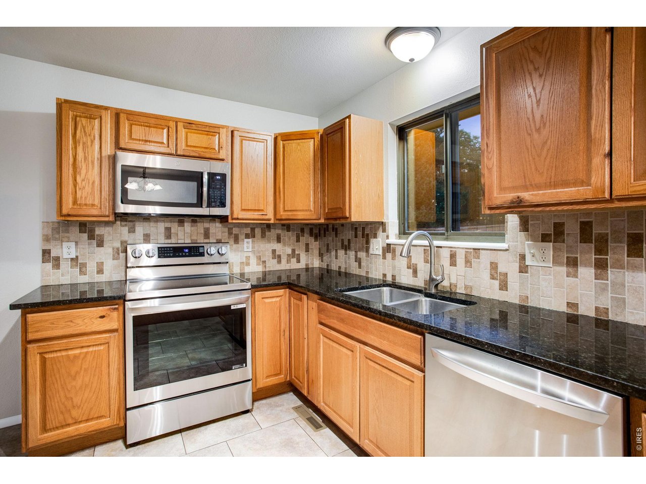 Property Photo 14 Cozy kitchen offers plenty of counterspace and cabinets, NEW stainless steel appliances which are all included, full tile backsplash, tile flooring, lazy Susan, and granite slab countertops