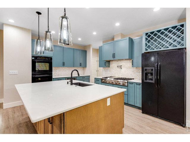 Property Photo 11 Gourmet kitchen features a center island, breakfast bar with underneath cabinets, quartz countertops, full glass backsplash, pot filler, stainless steel appliances with a 48 gas range and double ovens (all appliances included)