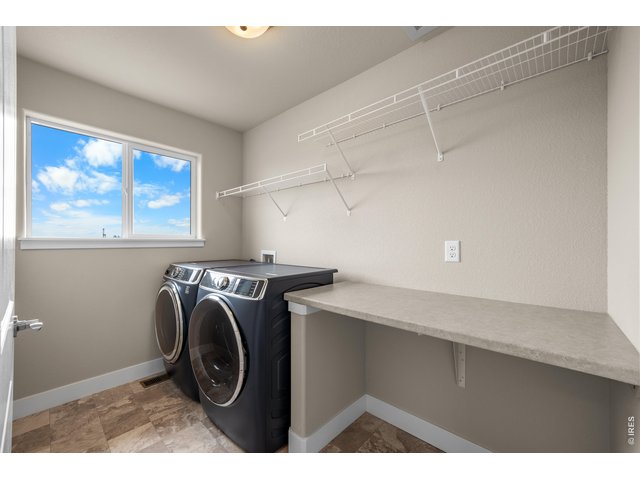 Property Photo 24 Upper Level Laundry Room with Folding Table and Hanging Shelves. Nice size window for lots of natural light. Dark Blue Washer and Dryer Included.