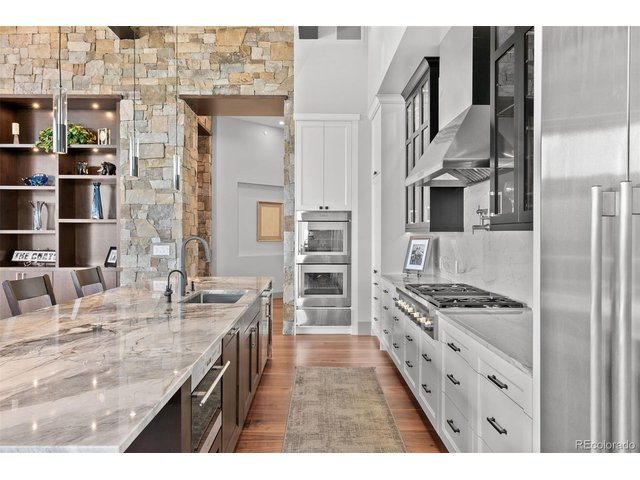 Property Photo 13 Highlighted by a magnificent 14-foot Quartzite Island with a waterfall edge, Thermador appliances, and custom Plato cabinetry