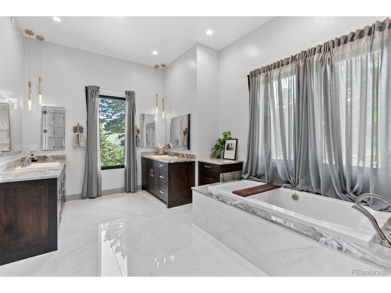 Dual Quartzite vanities and custom lighting, a soaking tub, and a glass-enclosed shower