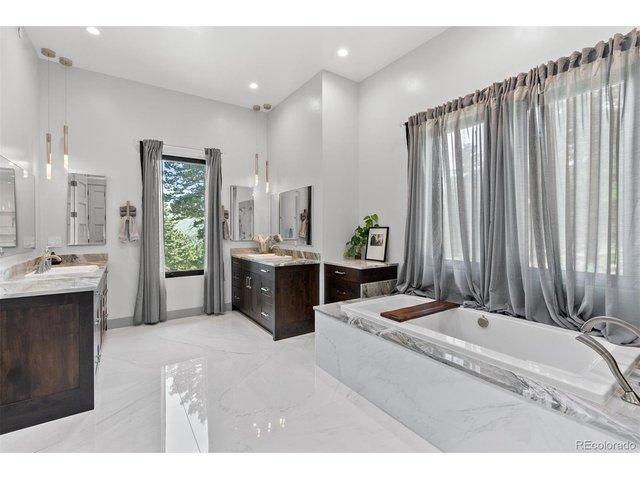 Property Photo 27 Dual Quartzite vanities and custom lighting, a soaking tub, and a glass-enclosed shower